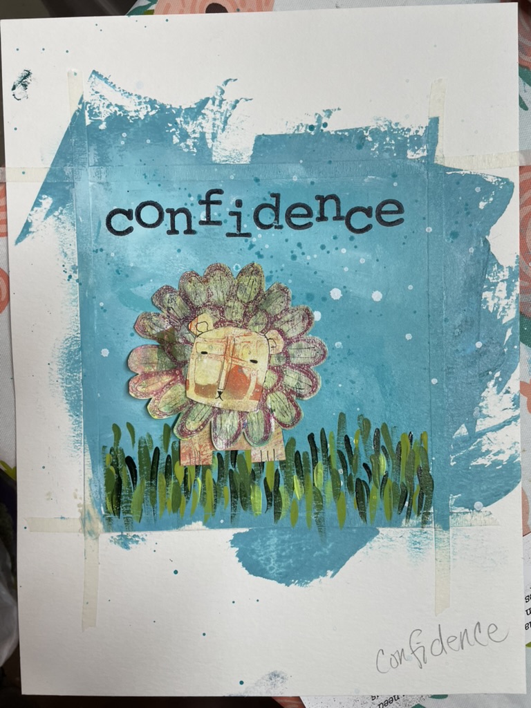 A small lion with a soft yellow face and a feathered green-and-pink mane stands in a row of green grass, against a turquoise printed background; the word “confidence” is stamped above in block letters.